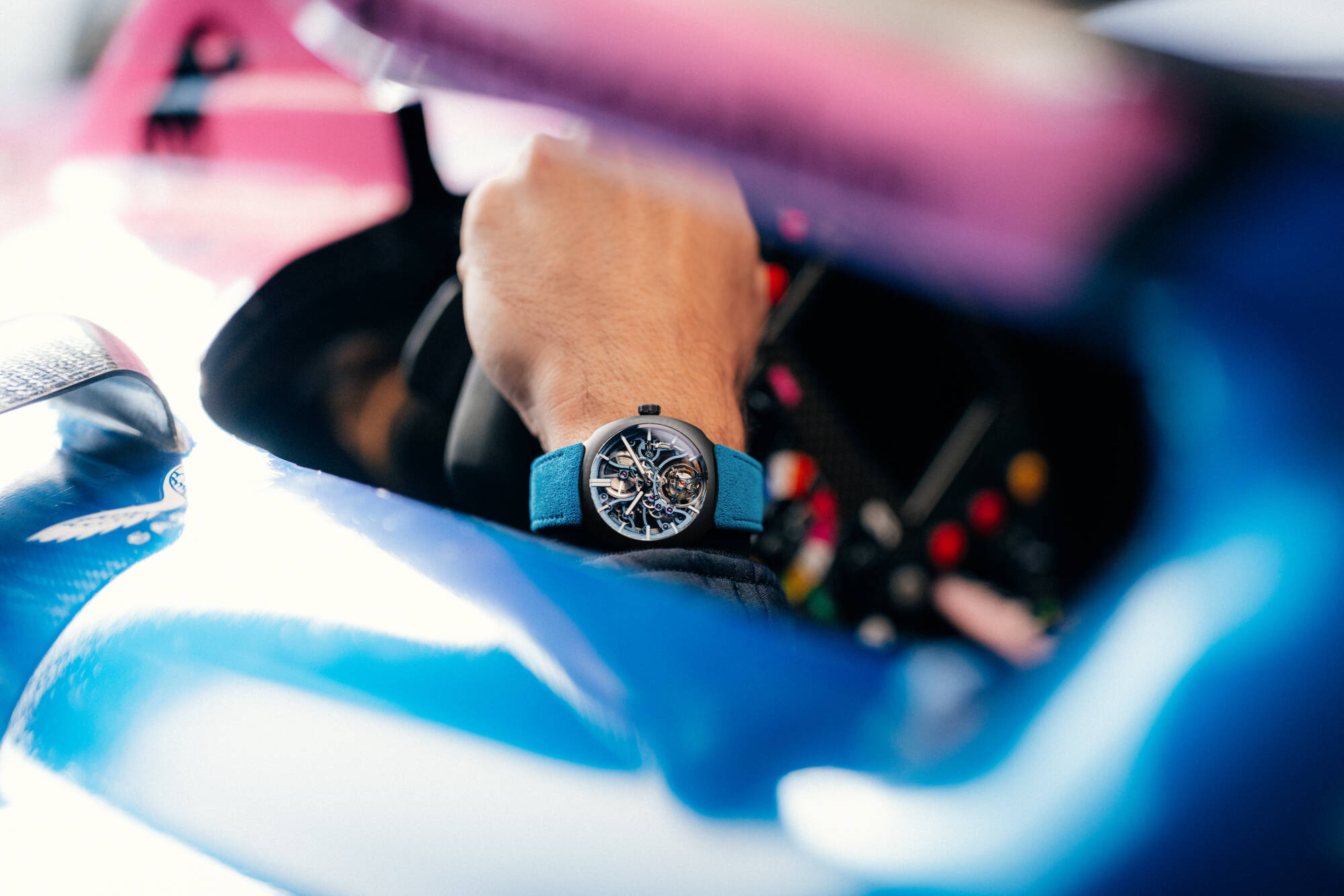 A hand at the wheel inside the cockpit of an Alpine car, watch on the wrist