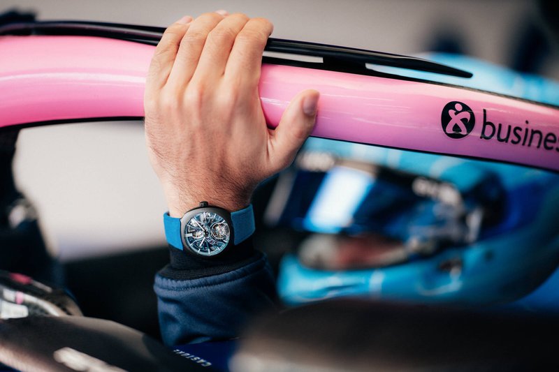 A hand gripping the pink halo of a racing car, watch visible